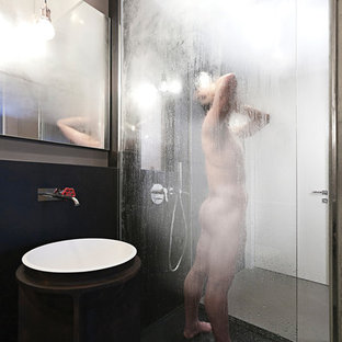 Cette photo montre un petit WC et toilettes avec un placard sans porte, un WC suspendu, un carrelage noir, du carrelage en ardoise, un mur beige, béton au sol, un lavabo de ferme et un sol gris.