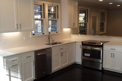 Inspiration for a mid-sized transitional l-shaped dark wood floor and brown floor kitchen pantry remodel in Other with an undermount sink, shaker cabinets, white cabinets, marble countertops, white backsplash, subway tile backsplash, stainless steel appliances, a peninsula and white countertops