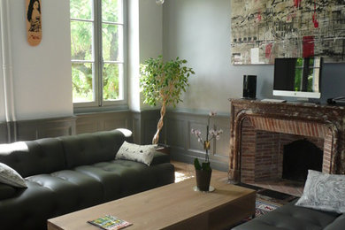 Imagen de salón abierto contemporáneo grande con paredes grises, suelo de madera en tonos medios, todas las chimeneas y marco de chimenea de piedra