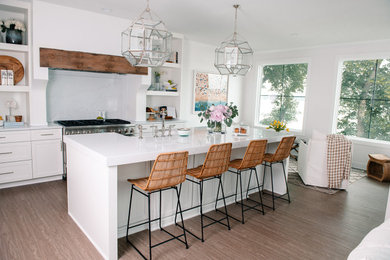 Inspiration for a coastal brown floor eat-in kitchen remodel in Other with a farmhouse sink, quartzite countertops, white backsplash, stone slab backsplash, stainless steel appliances, an island and white countertops