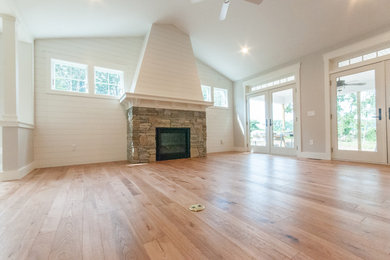 Living room - large open concept light wood floor living room idea in Providence with white walls, a standard fireplace and a stone fireplace