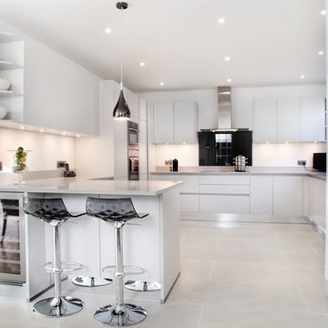 Light grey handle-less kitchen with black splash back
