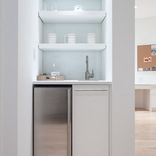 シカゴの小さいコンテンポラリースタイルのおしゃれなウェットバー (クオーツストーンカウンター、白いキッチンパネル、ガラス板のキッチンパネル、アンダーカウンターシンク、フラットパネル扉のキャビネット、白いキャビネット、淡色無垢フローリング、茶色い床、白いキッチンカウンター) の写真