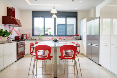 Large trendy l-shaped ceramic tile and beige floor enclosed kitchen photo with flat-panel cabinets, white cabinets, glass sheet backsplash, colored appliances, multicolored backsplash and an island