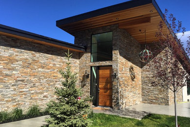 Example of a mid-sized trendy beige one-story stone house exterior design in Calgary with a shed roof