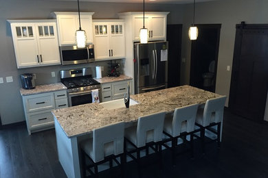 Mid-sized minimalist single-wall dark wood floor eat-in kitchen photo in Other with a farmhouse sink, flat-panel cabinets, white cabinets, granite countertops, blue backsplash, stainless steel appliances and an island