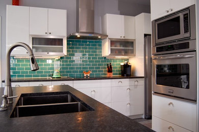 Large minimalist galley medium tone wood floor and gray floor eat-in kitchen photo in Raleigh with a double-bowl sink, flat-panel cabinets, white cabinets, granite countertops, blue backsplash, subway tile backsplash, stainless steel appliances and an island