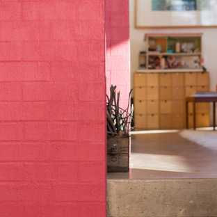 Esempio di un piccolo soggiorno contemporaneo aperto con pareti rosa, pavimento in cemento, stufa a legna e cornice del camino in mattoni