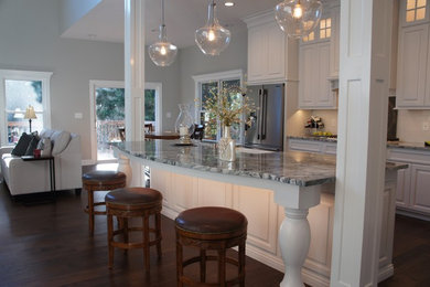Open concept kitchen - transitional single-wall dark wood floor open concept kitchen idea in Other with raised-panel cabinets, white cabinets, granite countertops, white backsplash, an island, a farmhouse sink and stainless steel appliances