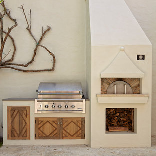 This is an example of a mediterranean backyard patio in Miami with an outdoor kitchen, tile and no cover.