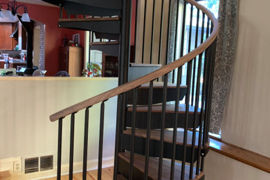 На фото: винтовая металлическая лестница среднего размера в стиле кантри с деревянными ступенями и перилами из смешанных материалов