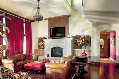 Example of a mid-sized tuscan open concept dark wood floor family room design in Denver with white walls, a standard fireplace, a stone fireplace and a wall-mounted tv