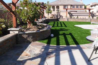 Trendy backyard stone patio photo in Los Angeles with a pergola