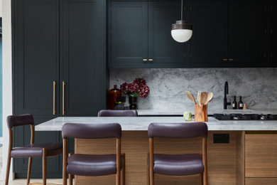 Expansive contemporary open plan kitchen in London with shaker cabinets, green cabinets, granite worktops, grey splashback, granite splashback, medium hardwood flooring, an island, grey worktops and feature lighting.