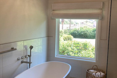 Example of a mid-sized minimalist master white tile and porcelain tile porcelain tile, beige floor and double-sink bathroom design in Phoenix with glass-front cabinets, beige cabinets, a one-piece toilet, white walls, an integrated sink, glass countertops, a hinged shower door, beige countertops and a floating vanity
