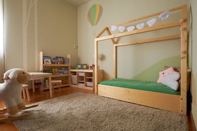 Foto di una piccola cameretta da letto da 1 a 3 anni nordica con pareti verdi e parquet chiaro