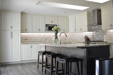 Inspiration for a large modern l-shaped kitchen in Sacramento with a double-bowl sink, beaded inset cabinets, beige cabinets, granite benchtops, white splashback, glass tile splashback, stainless steel appliances, laminate floors, with island, multi-coloured floor and multi-coloured benchtop.