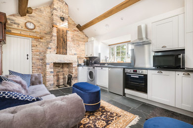 Farmhouse single-wall open plan kitchen in Other with shaker cabinets, white cabinets, grey splashback, mosaic tiled splashback, stainless steel appliances, no island, grey floors, grey worktops, exposed beams and a vaulted ceiling.