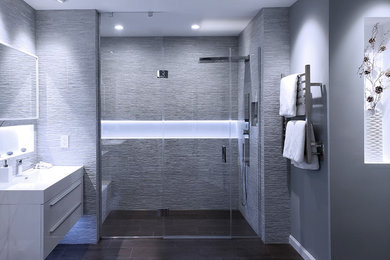 Inspiration for a large contemporary master gray tile and porcelain tile porcelain tile and brown floor bathroom remodel with flat-panel cabinets, white cabinets, a one-piece toilet, gray walls, an integrated sink, a hinged shower door and white countertops