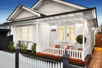 This is an example of a traditional one-storey white house exterior in Melbourne with wood siding and a metal roof.