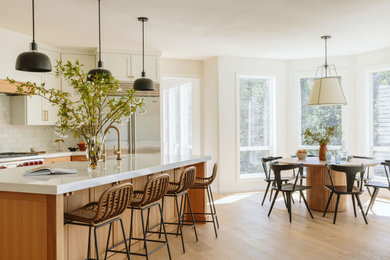 Example of a light wood floor kitchen design in Portland with shaker cabinets, light wood cabinets, quartz countertops, white backsplash, marble backsplash, stainless steel appliances, an island and white countertops