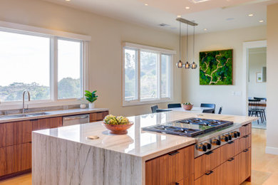 Inspiration for a large u-shaped light wood floor eat-in kitchen remodel in San Francisco with an undermount sink, flat-panel cabinets, beige cabinets, quartz countertops, green backsplash, glass tile backsplash, stainless steel appliances, an island and gray countertops