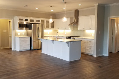 Open concept kitchen - mid-sized transitional l-shaped vinyl floor and brown floor open concept kitchen idea in Dallas with an undermount sink, shaker cabinets, white cabinets, granite countertops, gray backsplash, subway tile backsplash, stainless steel appliances, an island and gray countertops