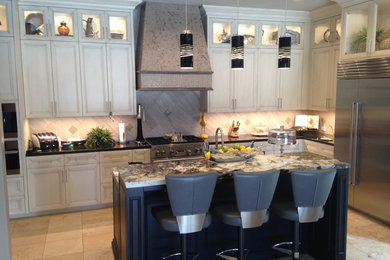 Inspiration for a transitional u-shaped travertine floor kitchen remodel in Phoenix with white cabinets, granite countertops, beige backsplash, stainless steel appliances, an island and recessed-panel cabinets