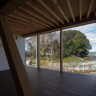 Foto di una camera da letto stile loft etnica di medie dimensioni con pareti bianche, parquet scuro, stufa a legna, cornice del camino in cemento e pavimento marrone