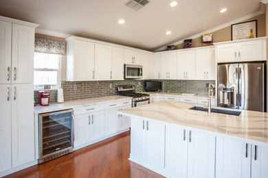 Inspiration for a transitional l-shaped eat-in kitchen in Sacramento with a single-bowl sink, shaker cabinets, white cabinets, quartz benchtops, grey splashback, glass tile splashback, stainless steel appliances and with island.