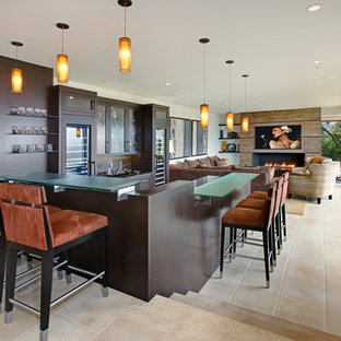 オレンジカウンティの巨大なコンテンポラリースタイルのおしゃれな着席型バー (濃色木目調キャビネット、ガラスカウンター、シェーカースタイル扉のキャビネット、茶色いキッチンパネル、木材のキッチンパネル、セラミックタイルの床、ベージュの床) の写真