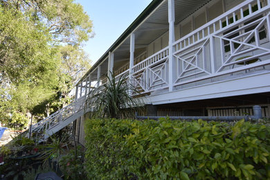 Large traditional one-storey white exterior in Brisbane with wood siding, a gable roof and a metal roof.