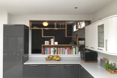 Photo of a large modern l-shaped open plan kitchen in Other with a submerged sink, flat-panel cabinets, grey cabinets, engineered stone countertops, green splashback, glass sheet splashback, integrated appliances, lino flooring, an island and grey floors.
