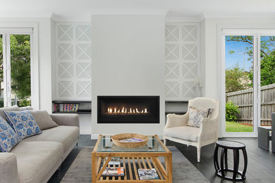 Mid-sized modern formal living room in Geelong with white walls, a standard fireplace, a plaster fireplace surround and black floor.