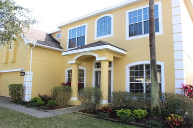 Elegant yellow two-story concrete house exterior photo in Tampa with a shingle roof