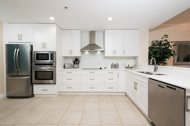 Example of a large trendy l-shaped porcelain tile eat-in kitchen design in Tampa with a double-bowl sink, recessed-panel cabinets, white cabinets, white backsplash, matchstick tile backsplash, stainless steel appliances and no island