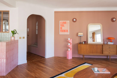 Cette image montre une grande entrée minimaliste avec un mur rose et un sol en bois brun.
