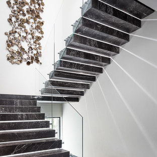 This is an example of a modern u-shaped glass railing staircase in Los Angeles with marble treads and marble risers.