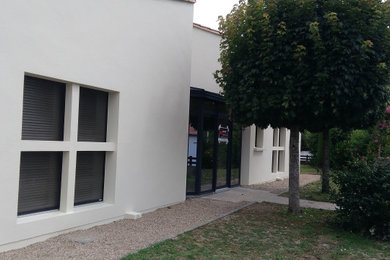 Exemple d'une porte d'entrée moderne de taille moyenne avec un mur beige, tomettes au sol, une porte simple, une porte noire et un sol marron.