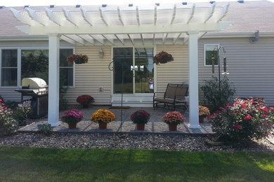 Mid-sized backyard concrete paver patio photo in Other with a pergola