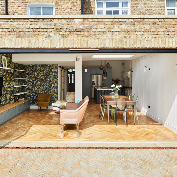 Modern open-plan kitchen extension with glass doors and herringbone flooring.