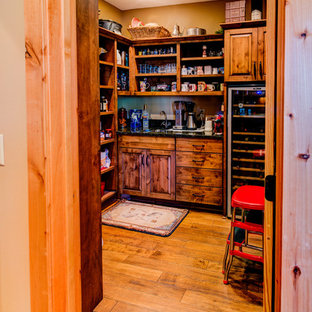 Exemple d'une arrière-cuisine montagne en L de taille moyenne avec un sol en bois brun, un sol marron, un évier encastré, un placard avec porte à panneau surélevé, des portes de placard en bois brun, un plan de travail en granite, une crédence grise, une crédence en ardoise, un électroménager en acier inoxydable et un îlot central.