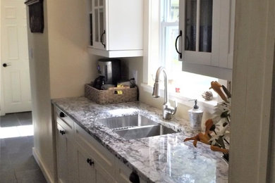 Small arts and crafts galley porcelain tile and gray floor enclosed kitchen photo in Other with a double-bowl sink, shaker cabinets, white cabinets, granite countertops, stainless steel appliances and no island