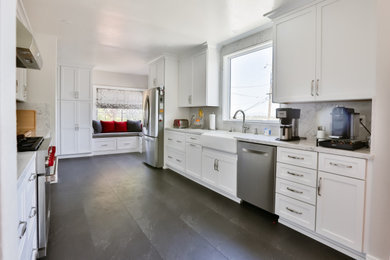 サンフランシスコにあるコンテンポラリースタイルのおしゃれなキッチン (エプロンフロントシンク、シェーカースタイル扉のキャビネット、白いキャビネット、シルバーの調理設備、アイランドなし、茶色い床、白いキッチンカウンター) の写真
