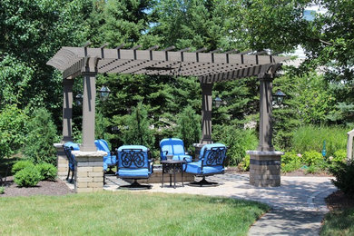 This is an example of a small traditional backyard patio in Indianapolis with a fire feature, brick pavers and a pergola.