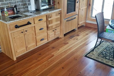 Eat-in kitchen - small rustic single-wall dark wood floor and brown floor eat-in kitchen idea in Atlanta with an undermount sink, flat-panel cabinets, light wood cabinets, granite countertops, brown backsplash, brick backsplash, paneled appliances, no island and multicolored countertops