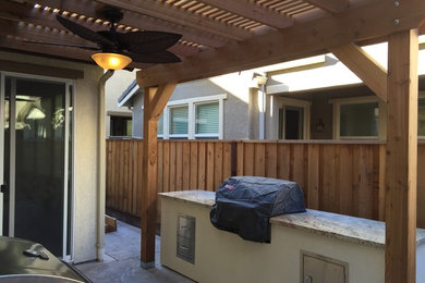 Ejemplo de patio de estilo americano de tamaño medio en patio trasero con cocina exterior, suelo de hormigón estampado y pérgola