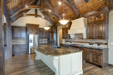 Inspiration for a large rustic galley light wood floor eat-in kitchen remodel in Wichita with an undermount sink, raised-panel cabinets, light wood cabinets, granite countertops, beige backsplash, stone tile backsplash, paneled appliances and an island