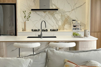 Photo of a large contemporary galley eat-in kitchen in Sydney with a single-bowl sink, flat-panel cabinets, medium wood cabinets, tile benchtops, multi-coloured splashback, marble splashback, black appliances, medium hardwood floors, with island, brown floor and white benchtop.