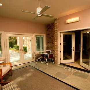 This is an example of a medium sized contemporary walk-out basement in Detroit with slate flooring, pink walls and no fireplace.